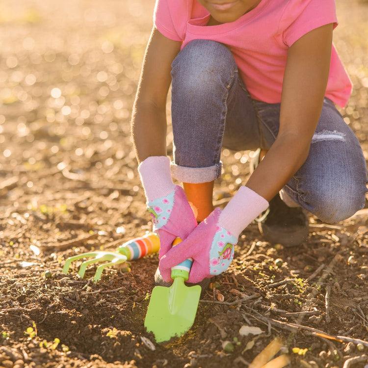 A kid playing with the Melissa & Doug Dixie and Trixie Ladybug Good Gripping Gardening Gloves