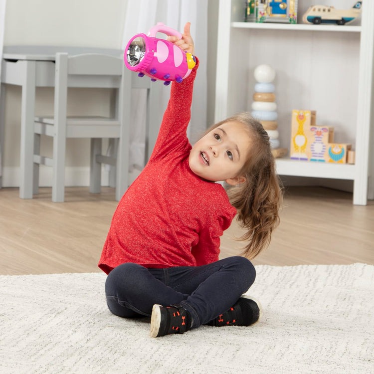 A kid playing with the Melissa & Doug Sunny Patch Trixie Ladybug Flashlight With Easy-Grip Handle