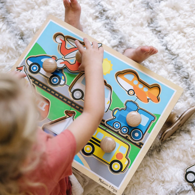 A kid playing with the Melissa & Doug Vehicles Jumbo Knob Wooden Puzzle (8 pcs)