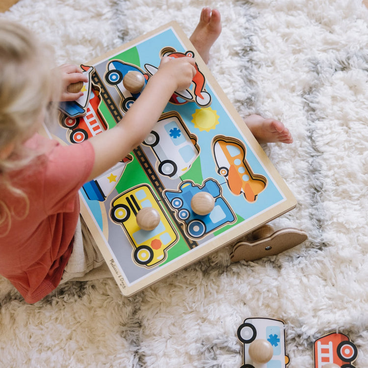 A kid playing with the Melissa & Doug Vehicles Jumbo Knob Wooden Puzzle (8 pcs)