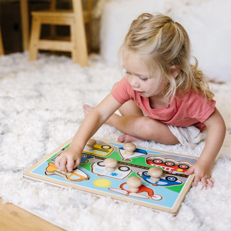 A kid playing with the Melissa & Doug Vehicles Jumbo Knob Wooden Puzzle (8 pcs)