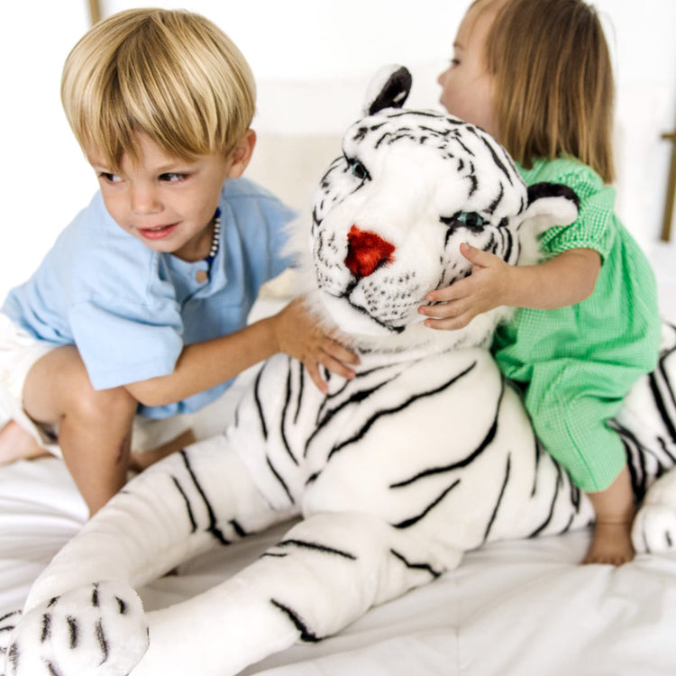 A kid playing with the Melissa & Doug Giant Siberian White Tiger - Lifelike Stuffed Animal (over 5 feet long)