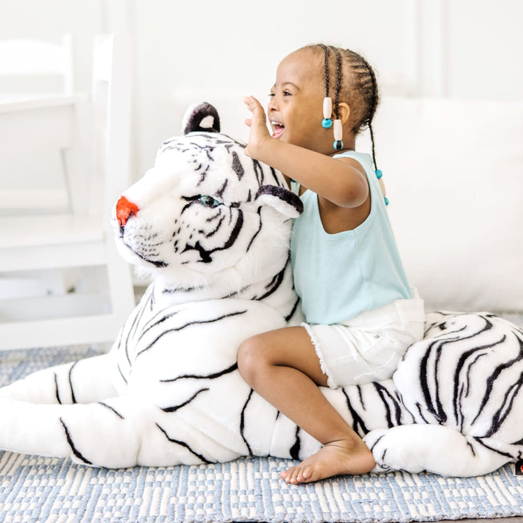 A kid playing with the Melissa & Doug Giant Siberian White Tiger - Lifelike Stuffed Animal (over 5 feet long)