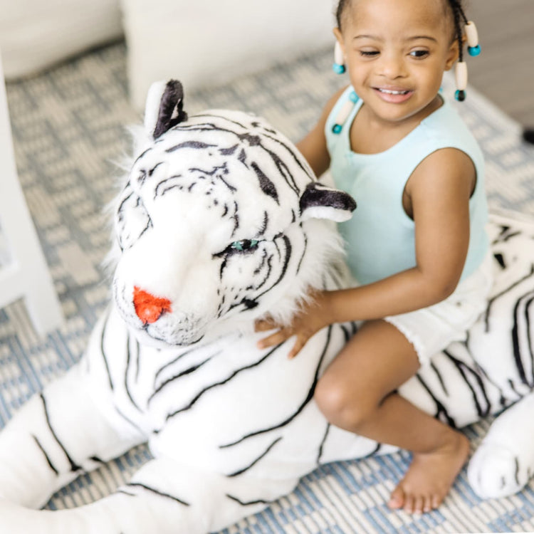 A kid playing with the Melissa & Doug Giant Siberian White Tiger - Lifelike Stuffed Animal (over 5 feet long)