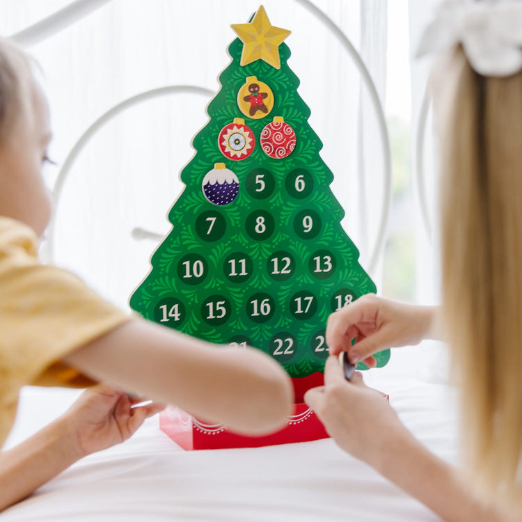 A kid playing with the Melissa & Doug Wooden Religious Advent Calendar - Magnetic Christmas Tree, 25 Magnets