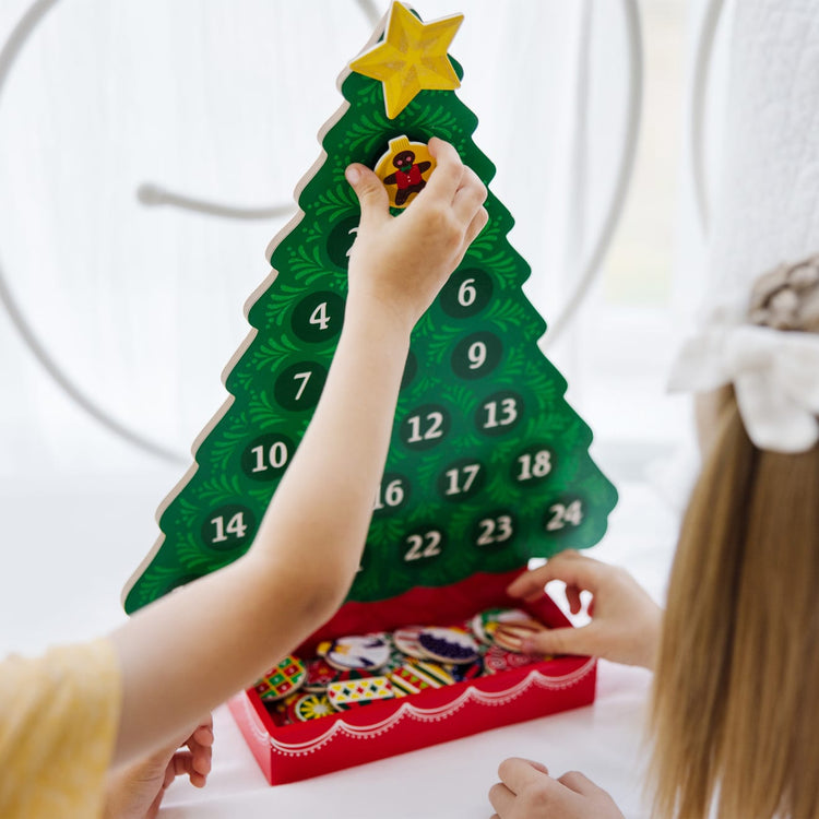 A kid playing with the Melissa & Doug Wooden Religious Advent Calendar - Magnetic Christmas Tree, 25 Magnets