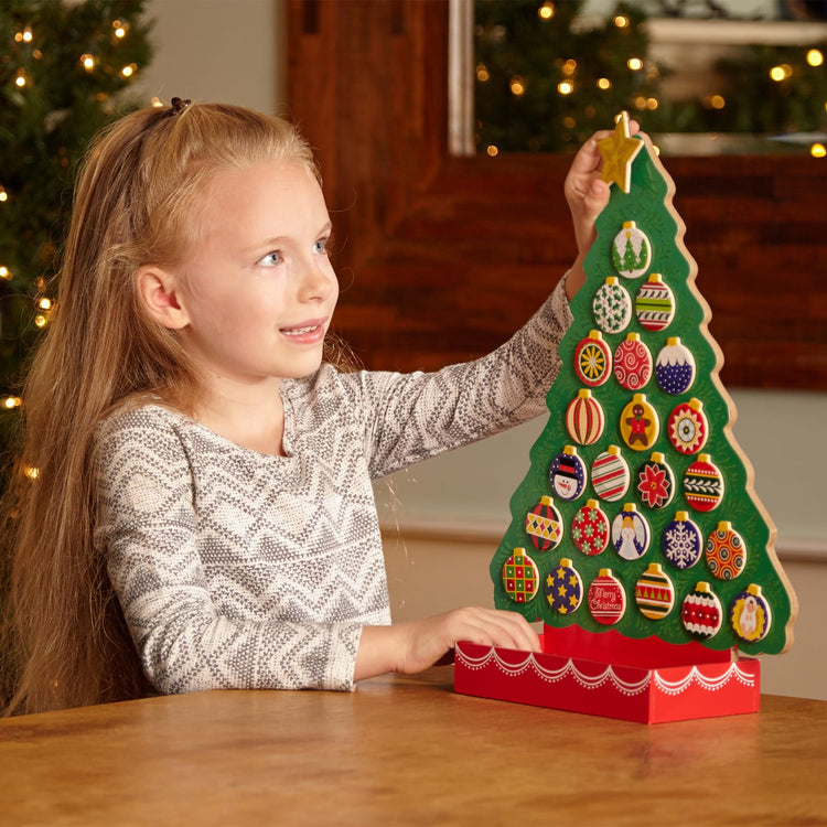 A kid playing with the Melissa & Doug Wooden Religious Advent Calendar - Magnetic Christmas Tree, 25 Magnets