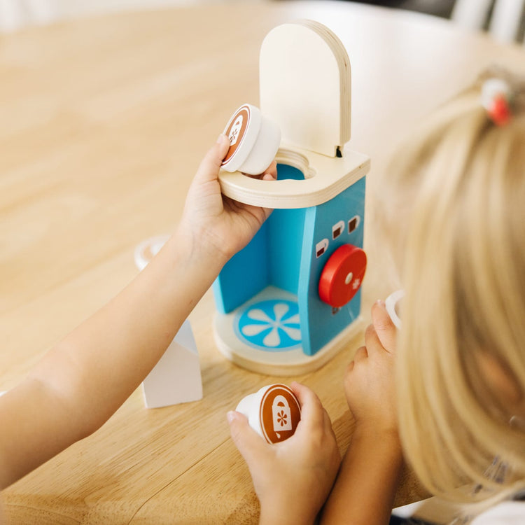 A kid playing with the Melissa & Doug 11-Piece Brew and Serve Wooden Coffee Maker Set - Play Kitchen Accessories