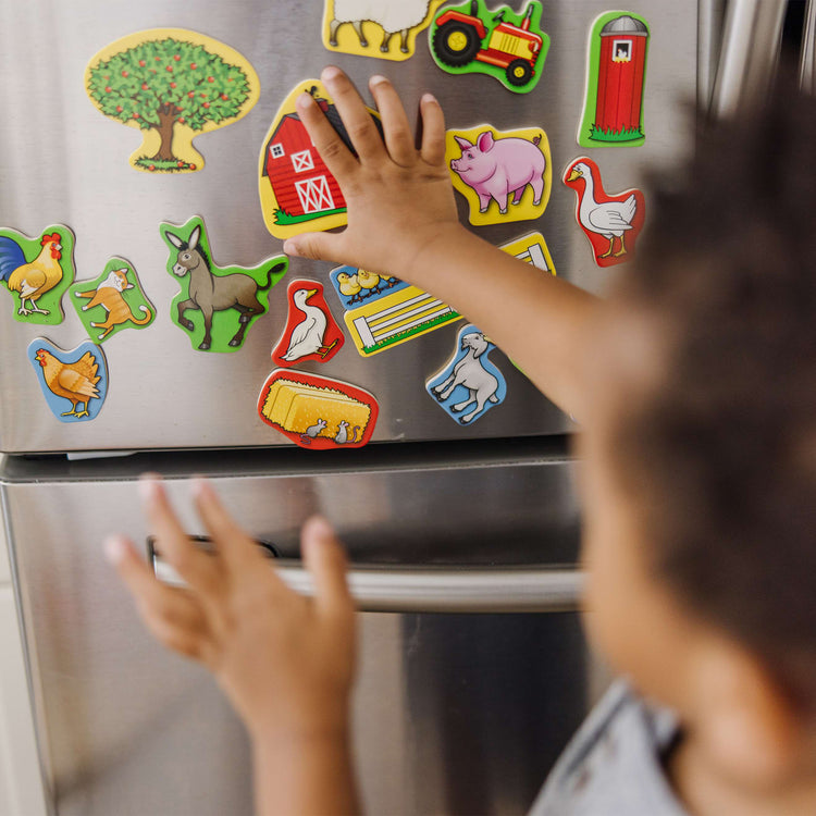 A kid playing with the Melissa & Doug 20 Wooden Farm Magnets in a Box