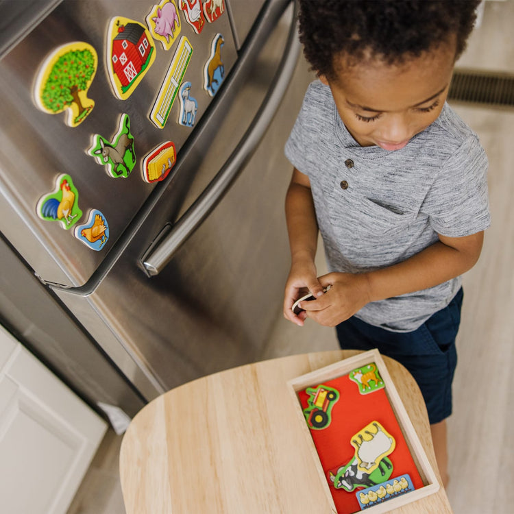 A kid playing with the Melissa & Doug 20 Wooden Farm Magnets in a Box