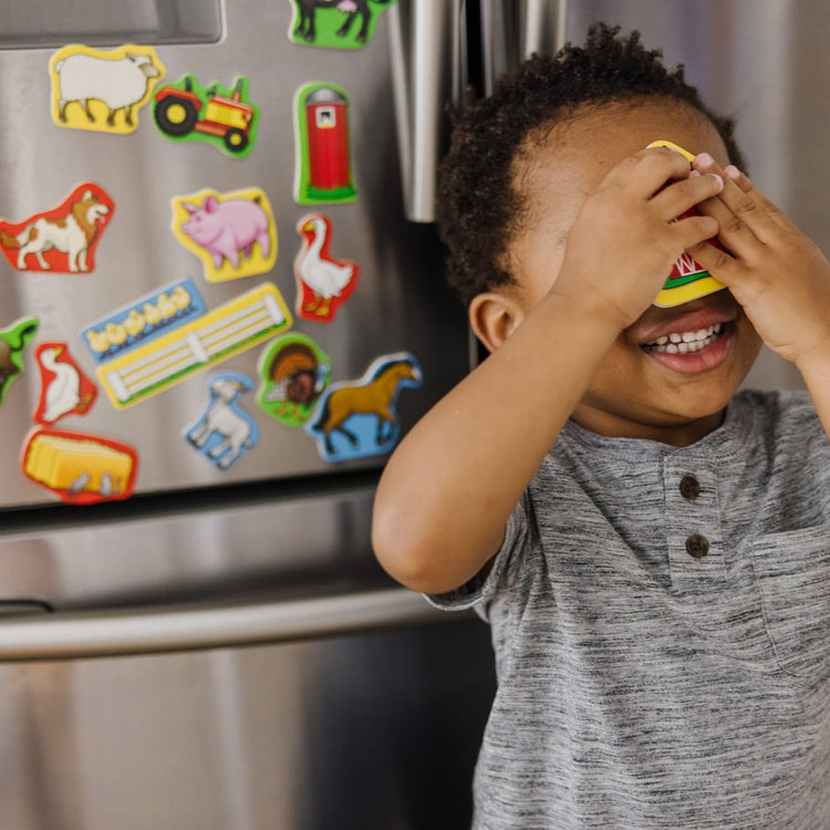 A kid playing with the Melissa & Doug 20 Wooden Farm Magnets in a Box