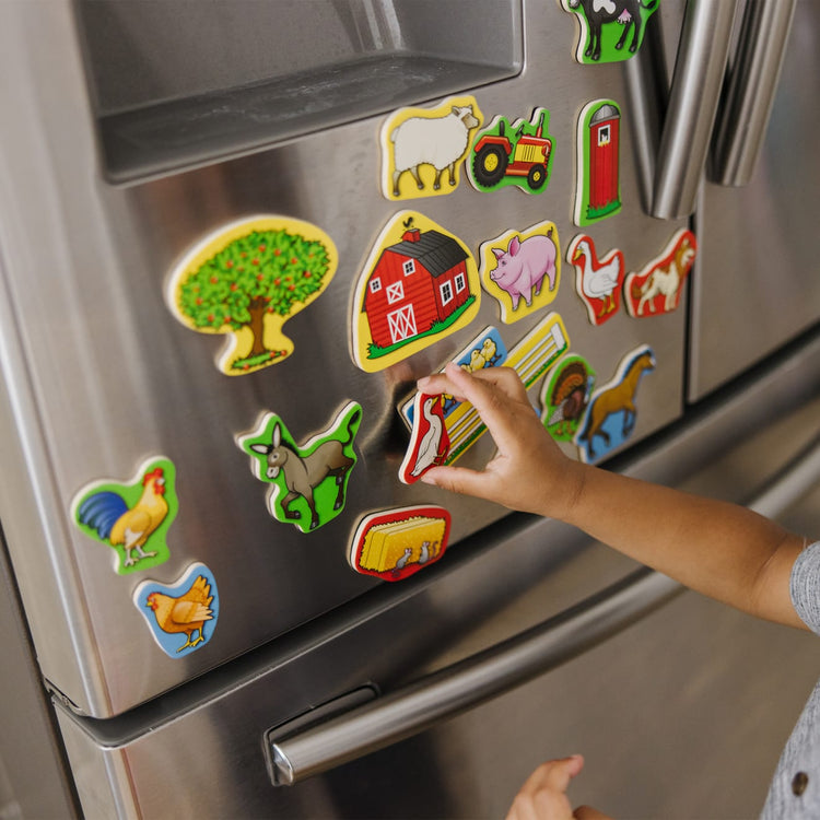 A kid playing with the Melissa & Doug 20 Wooden Farm Magnets in a Box