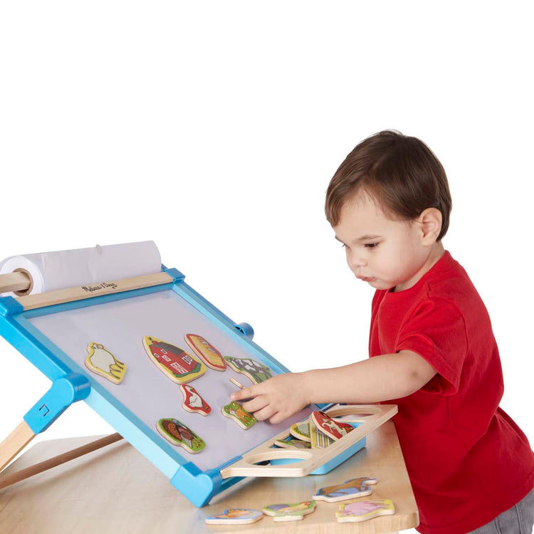 A child on white background with the Melissa & Doug 20 Wooden Farm Magnets in a Box