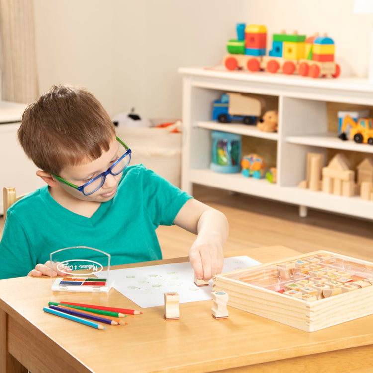 A kid playing with the Melissa & Doug Wooden Stamp Set, Favorite Things - 26 Wooden Stamps, 4-Color Stamp Pad