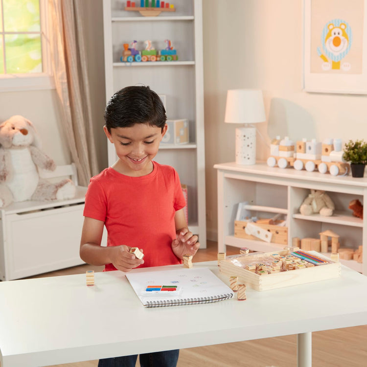 A kid playing with the Melissa & Doug Wooden Stamp Set, Favorite Things - 26 Wooden Stamps, 4-Color Stamp Pad