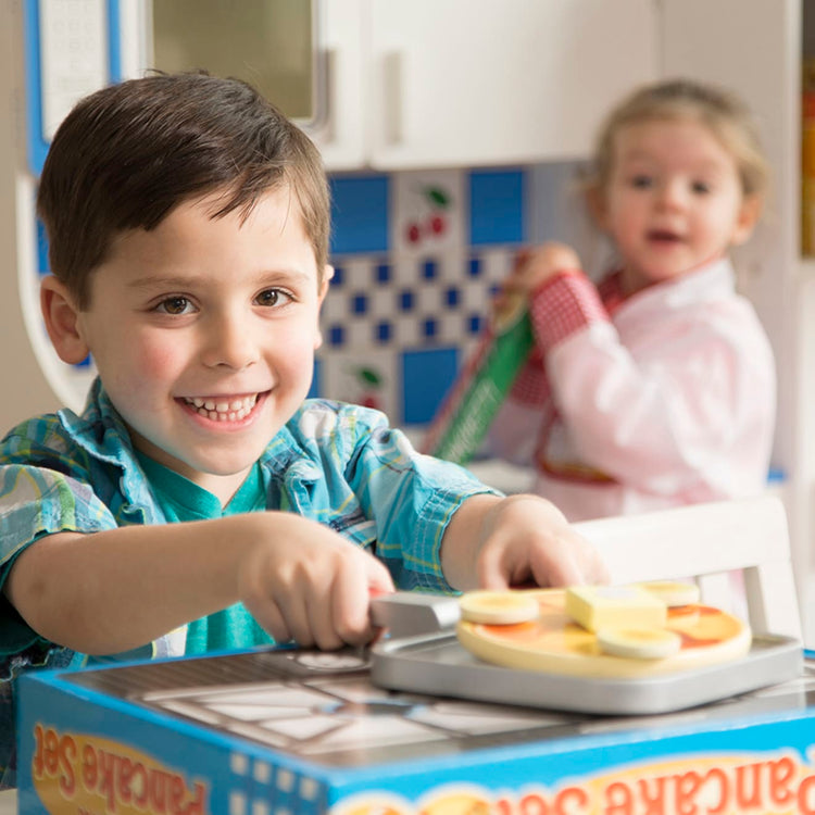 A kid playing with the Melissa & Doug Flip and Serve Pancake Set (19 pcs) - Wooden Breakfast Play Food