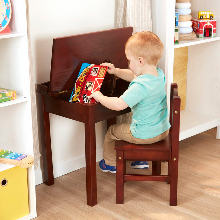 A kid playing with the Melissa & Doug Wooden Child's Lift-Top Desk & Chair - Espresso