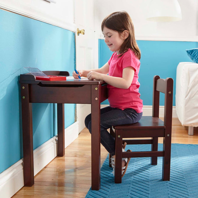 A kid playing with the Melissa & Doug Wooden Child's Lift-Top Desk & Chair - Espresso