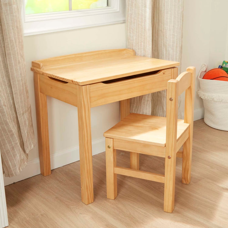 A kid playing with the Melissa & Doug Wooden Child's Lift-Top Desk & Chair - Honey