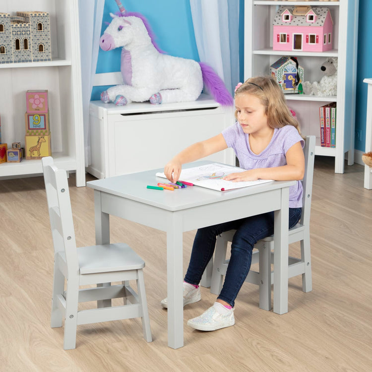 A kid playing with the Melissa & Doug Kids Furniture Wooden Table and 2 Chairs - Gray