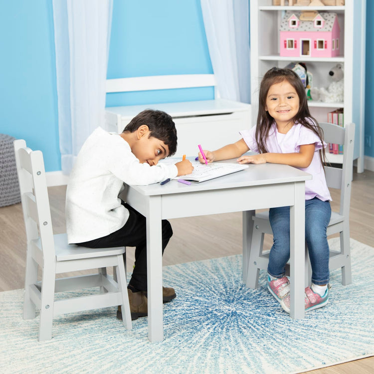 A kid playing with the Melissa & Doug Kids Furniture Wooden Table and 2 Chairs - Gray