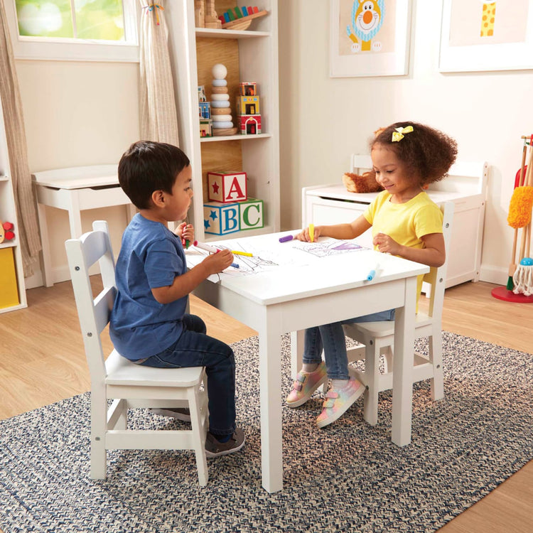 A kid playing with the Melissa & Doug Wooden Kids Table and 2 Chairs Set - White Furniture for Playroom