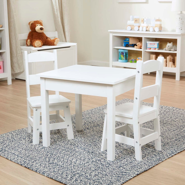 A kid playing with the Melissa & Doug Wooden Kids Table and 2 Chairs Set - White Furniture for Playroom