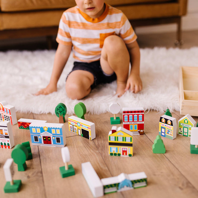 A kid playing with the Melissa & Doug Wooden Town Play Set With Storage Tray (32 pcs)