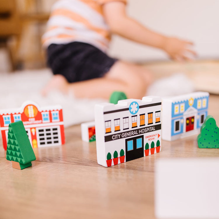 A kid playing with the Melissa & Doug Wooden Town Play Set With Storage Tray (32 pcs)