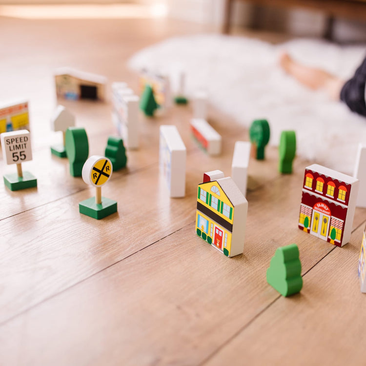 A kid playing with the Melissa & Doug Wooden Town Play Set With Storage Tray (32 pcs)