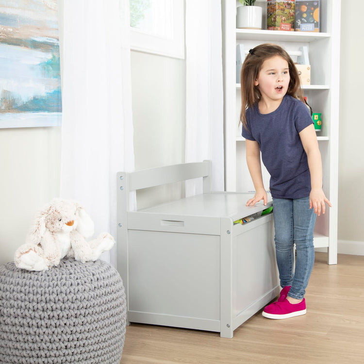 A kid playing with the Melissa & Doug Wooden Toy Chest (Gray)